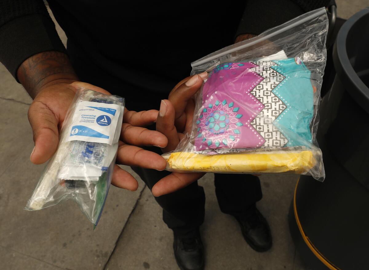 Deandre Fradiue, who works as an attendant for the portable Pit Stop restroom at Oakwood and Madison Avenues in East Hollywood, shows hygiene kits available for men and women.