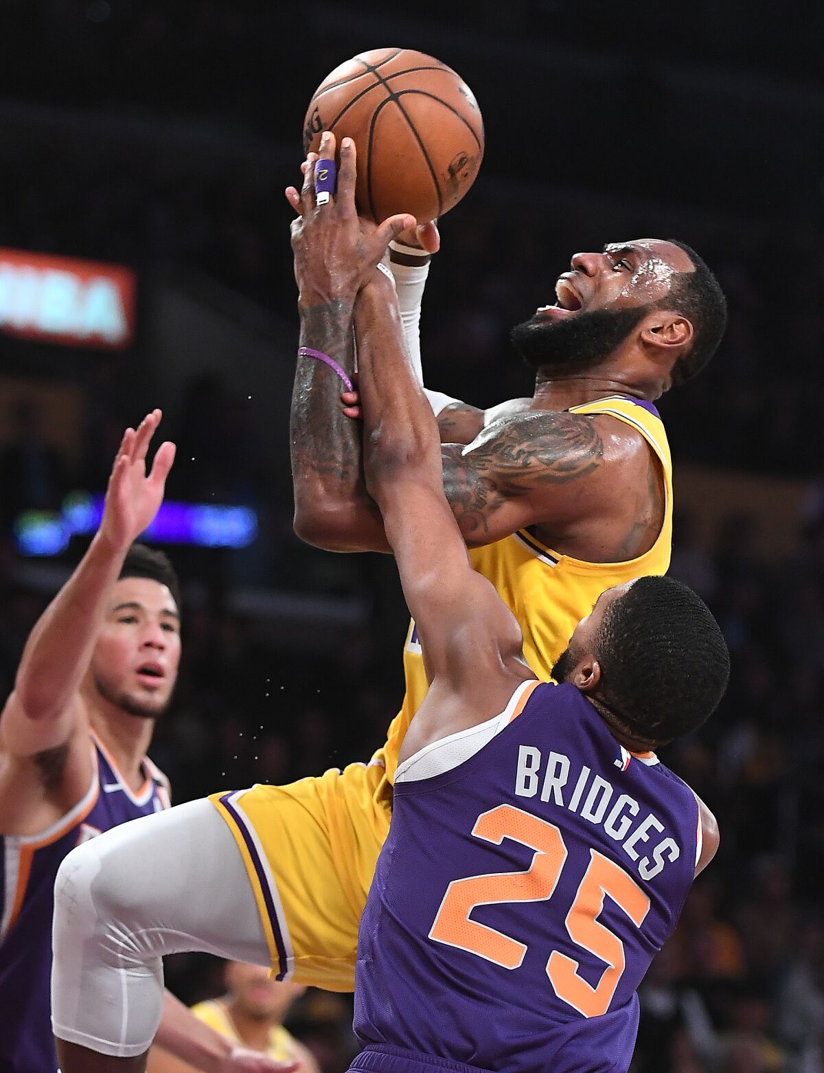 Lakers' LeBron James is fouled by Phoenix Suns' Mikal Bridges while driving to the basket in the third quarter at Staples Center on Monday