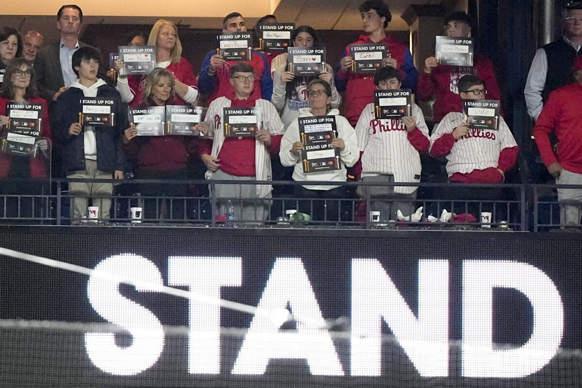First Lady Jill Biden, third from left in front, hold signs for Stand Up To Cancer between the fifth and sixth innings in Game 4 of baseball's World Series between the Houston Astros and the Philadelphia Phillies on Wednesday, Nov. 2, 2022, in Philadelphia. (AP Photo/David J. Phillip)