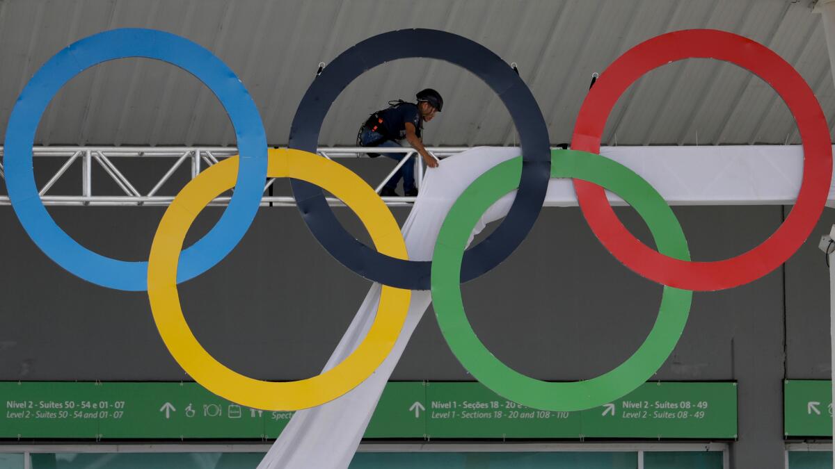 A worker covers scaffolding holding the Olympic rings at Olympic Park ahead of the 2016 Summer Games in Rio.