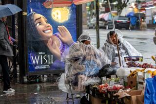 LOS ANGELES, CA - NOVEMBER 15, 2023: Wrapped in clear plastic rain coats, street vendors try and stay dry from a late afternoon rain storm while selling their fruits during a in Boyle Heights on November 15, 2023 in Los Angeles, California.(Gina Ferazzi / Los Angeles Times)