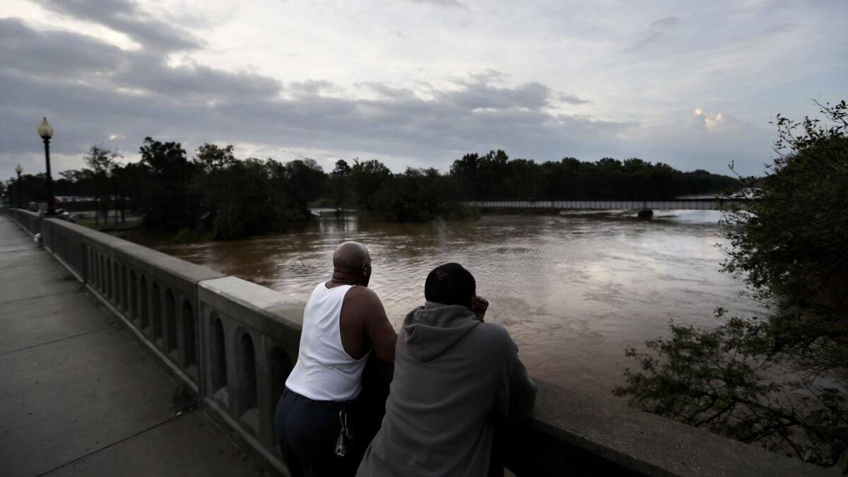 Gerald Generette, right, and Maurice Miller watch the rising Cape Fear River flow by in Fayetteville, N.C., on Monday.