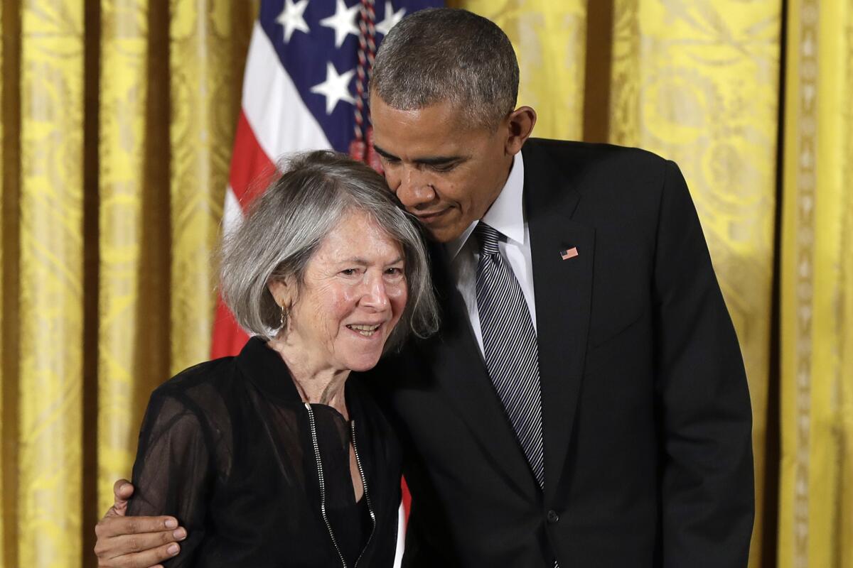 Poet Louise Gluck, a white woman with grey hair, is embraced by President Barack Obama at a ceremony.