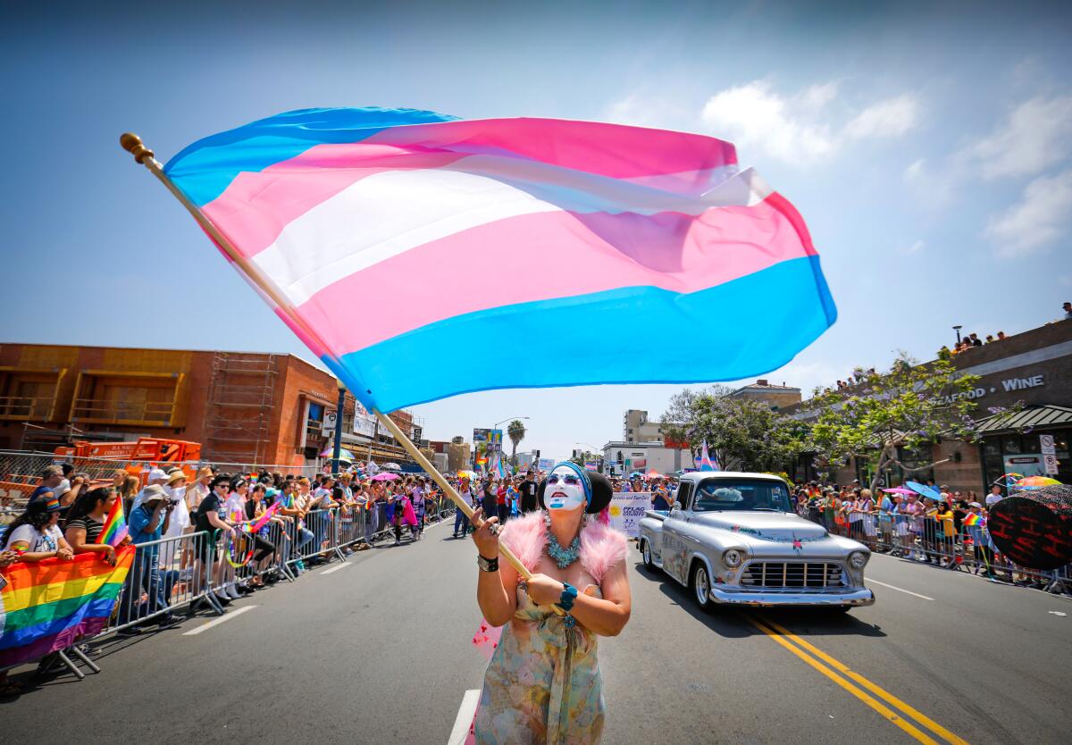 Sister Yesate of the Sisters of Perpetual Indulgence waves a transgender flag while walking the 2019 San Diego Pride Parade in Hillcrest.