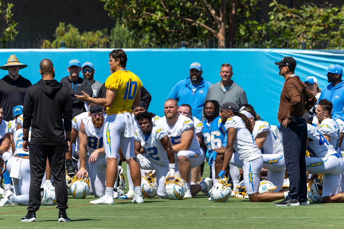 Chargers quarterback Justin Herbert addresses the team as coach Jim Harbaugh, right, watches.