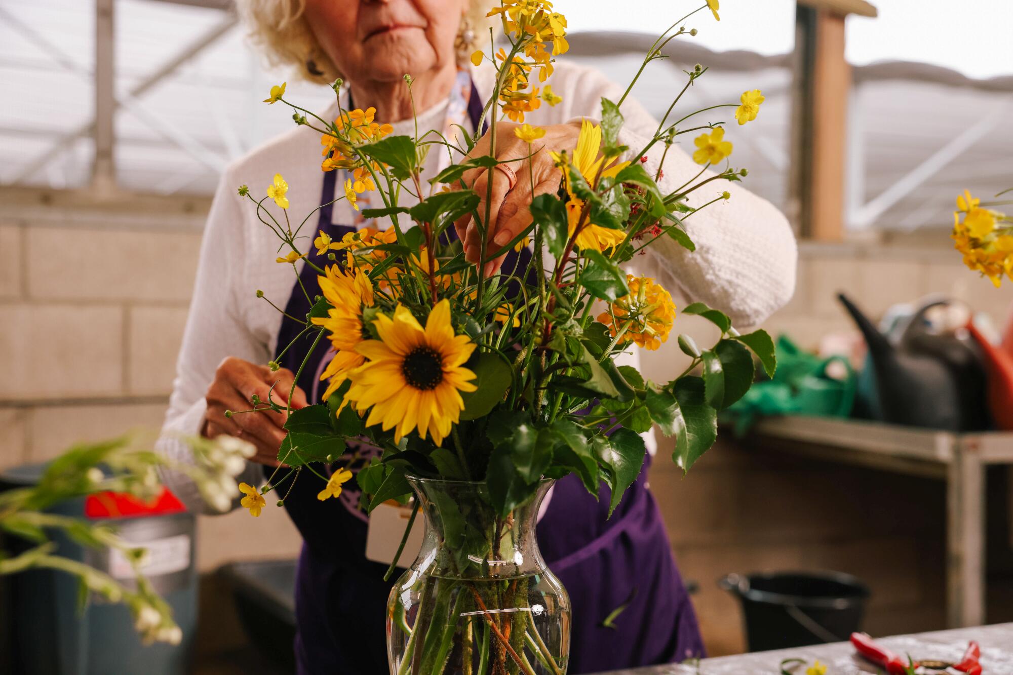 A woman assembles a bouquet made from native foliage and flowers.