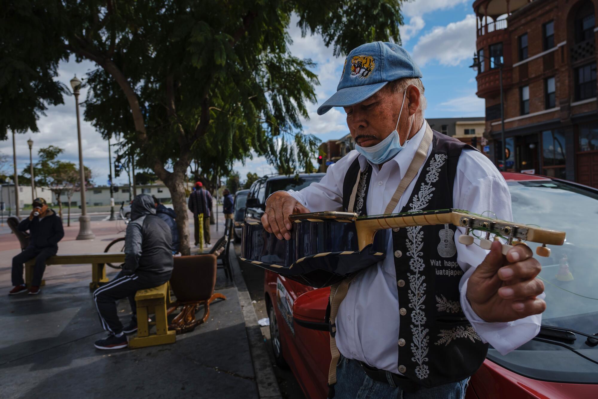 Santos Monge, 58, tunes his vihuela (a small guitar) as he awaits work as a musician at Mariachi Plaza in Los Angeles.