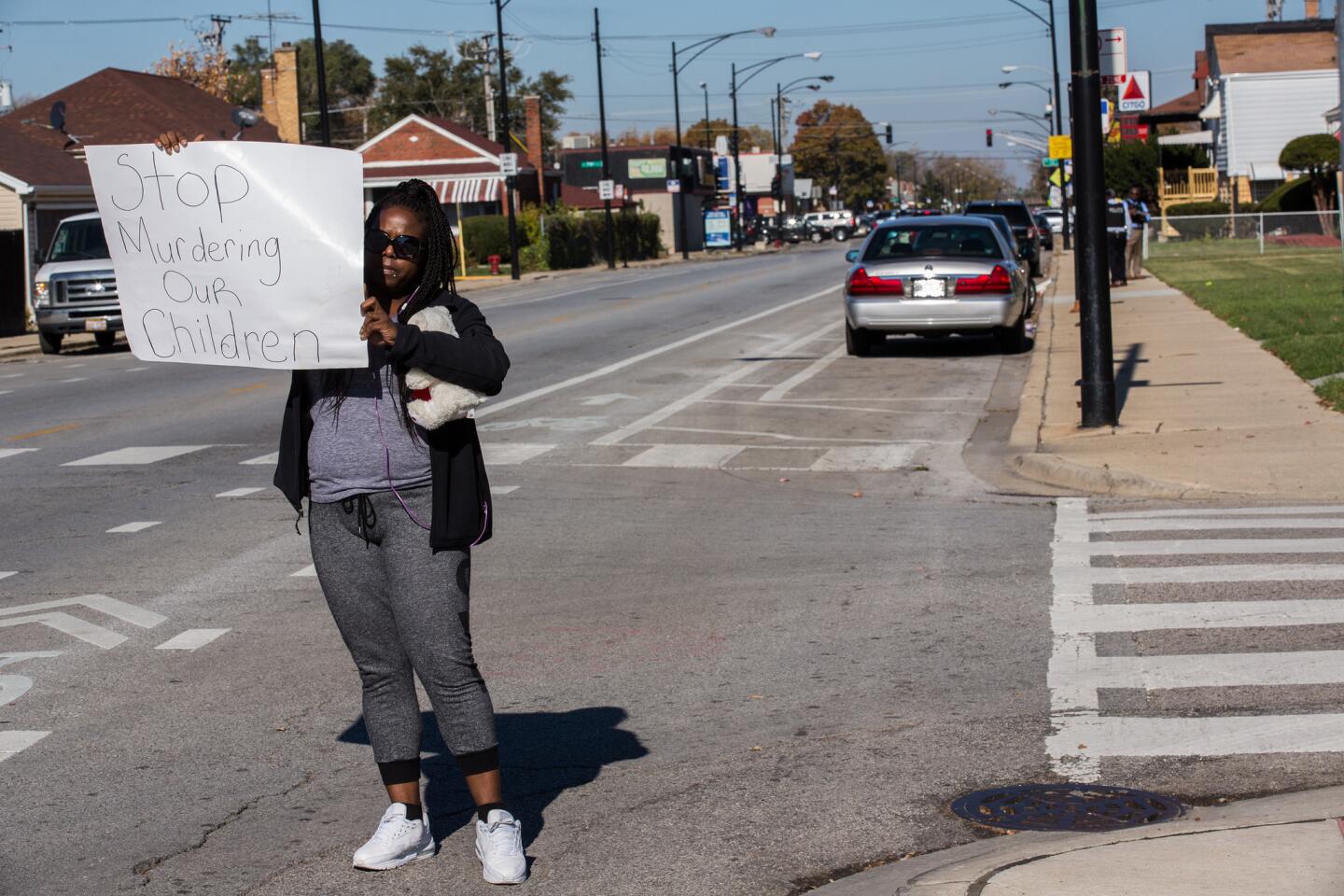 Kaisha Cole, 32, holds a sign at South Damen Avenue near 80th Street on Nov. 3, 2015, as Chicago police investigate the death of 9-year-old Tyshawn Lee. The boy was fatally shot the day before in the Gresham neighborhood.
