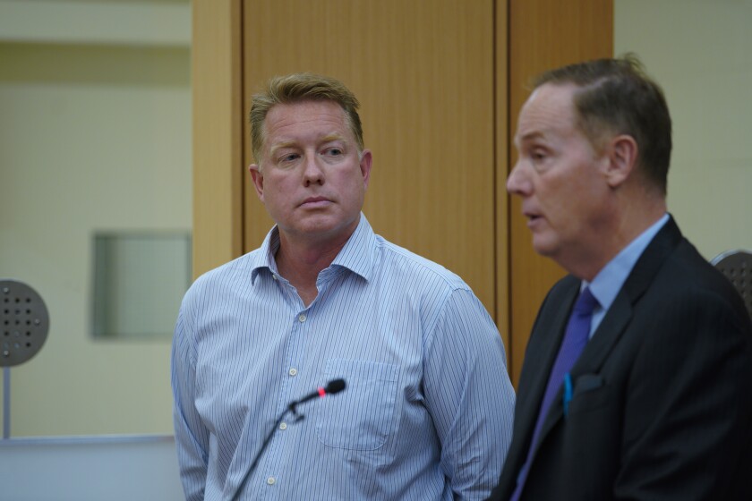 A man stands next to his lawyer in court