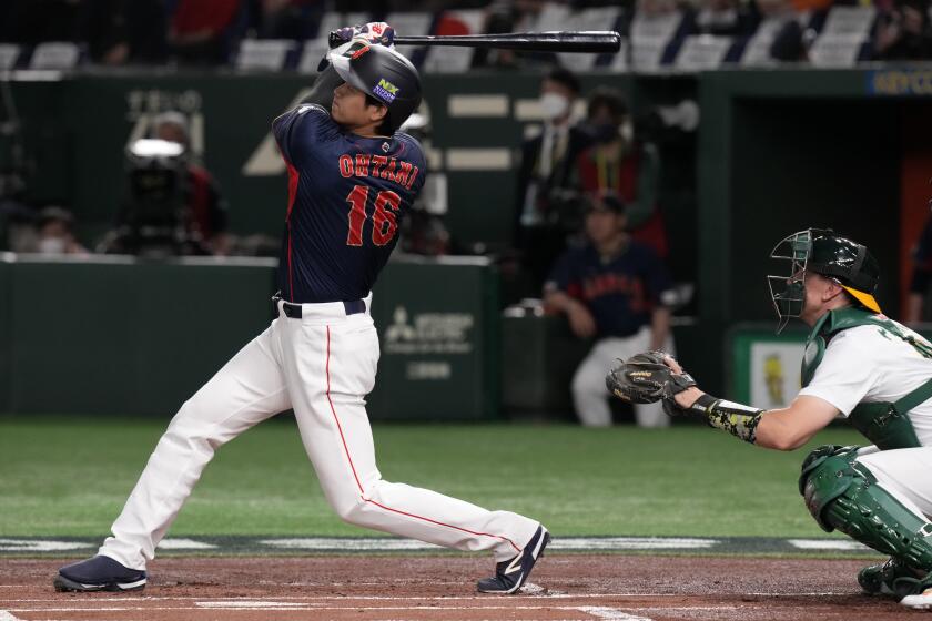 Shohei Ohtani of Japan hits a 3-run home run as Robert Perkins of Australia, right, watches during their Pool B game at the World Baseball Classic at the Tokyo Dome Sunday, March 12, 2023, in Tokyo. (AP Photo/Eugene Hoshiko)