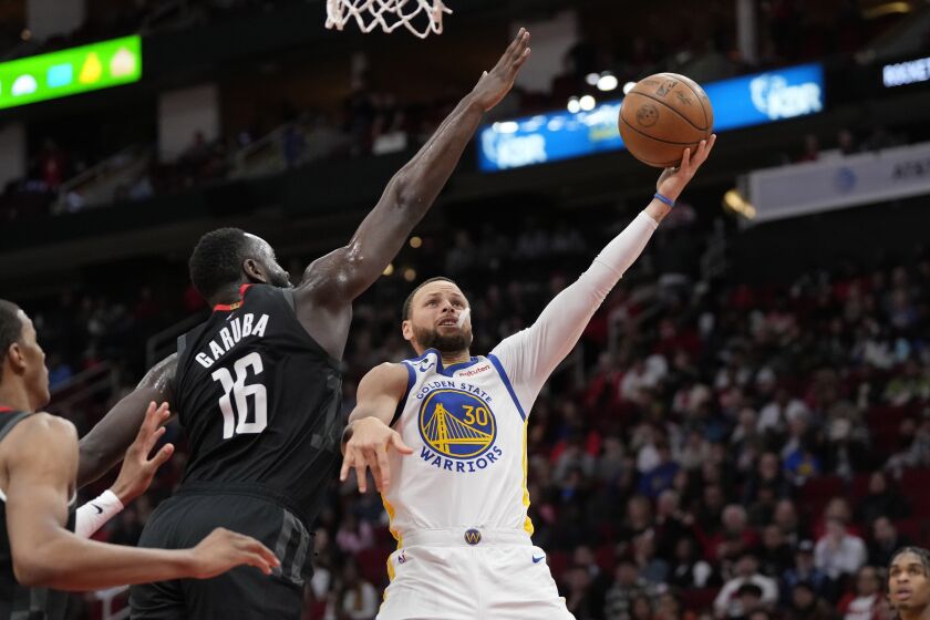 Golden State Warriors' Stephen Curry (30) shoots as Houston Rockets' Usman Garuba (16) defends during the second half of an NBA basketball game Monday, March 20, 2023, in Houston. The Warriors won 121-108. (AP Photo/David J. Phillip)