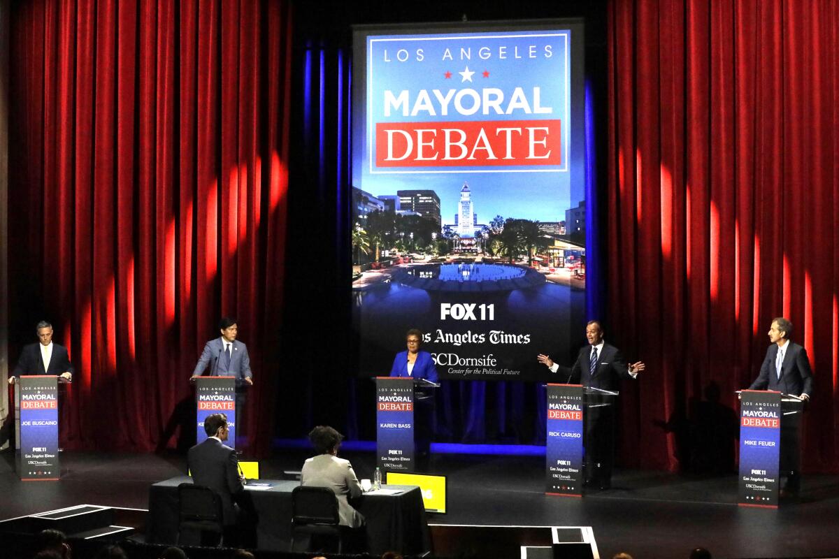 People stand at podiums on a debate stage