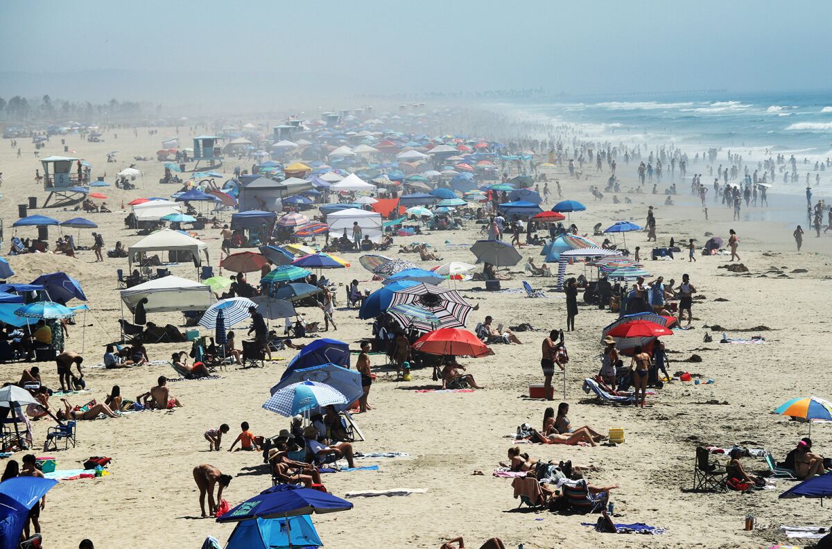 Thousands of beachgoers use umbrellas to escape from the hot temperatures.