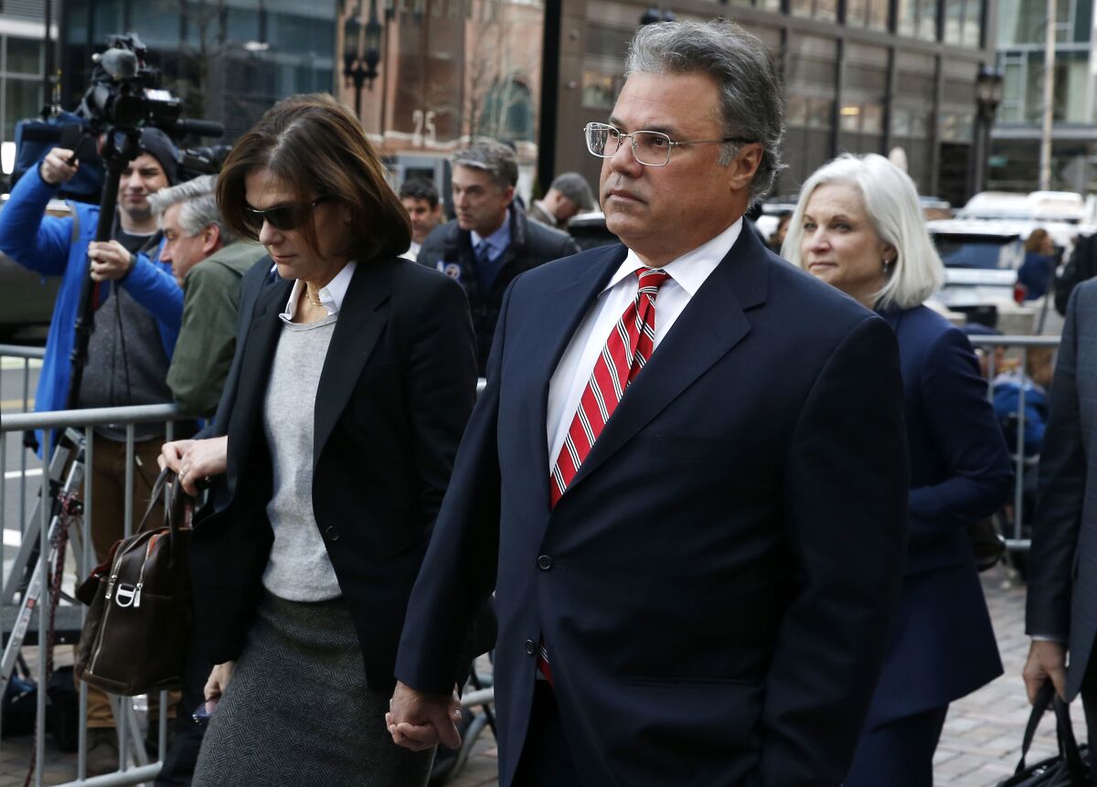 Elizabeth Henriquez, left, and her husband, Manuel, leave the federal courthouse in Boston last year. Elizabeth Henriquez was sentenced Tuesday; her husband will appear before a judge next week.