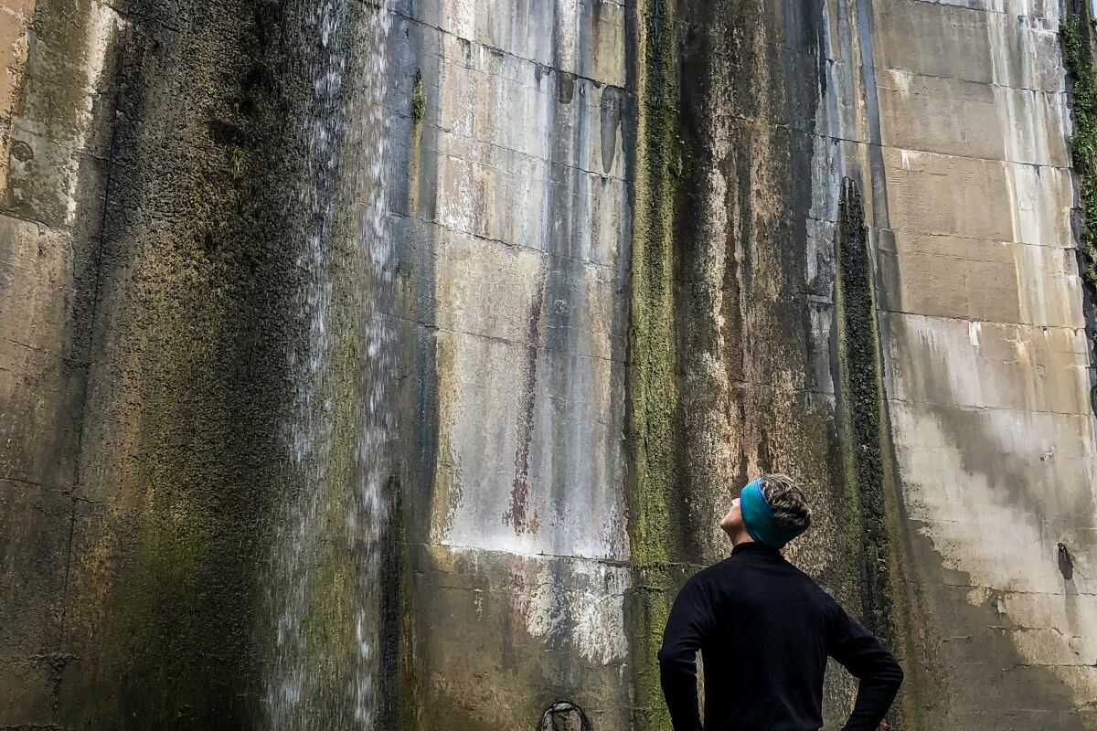 A man looks up at a dam on a trail in Pasadena.