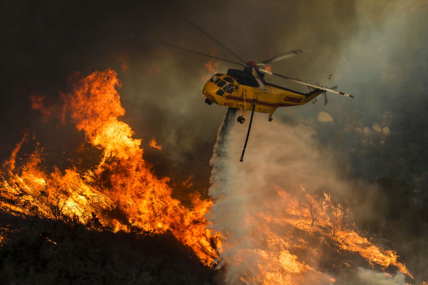 A helicopter fighting the Holy fire drops water on flames at North Main Divide along Ortega Highway.