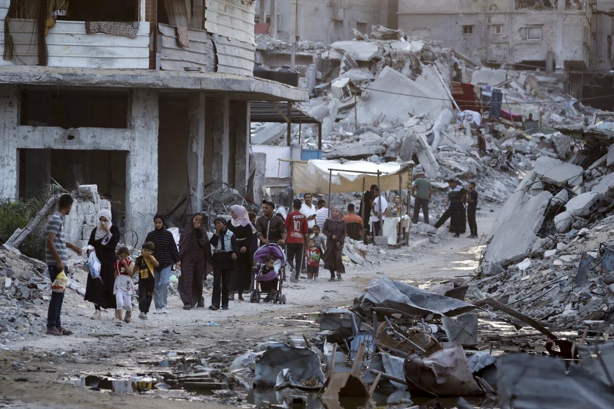 Displaced Palestinians walk amid rubble.
