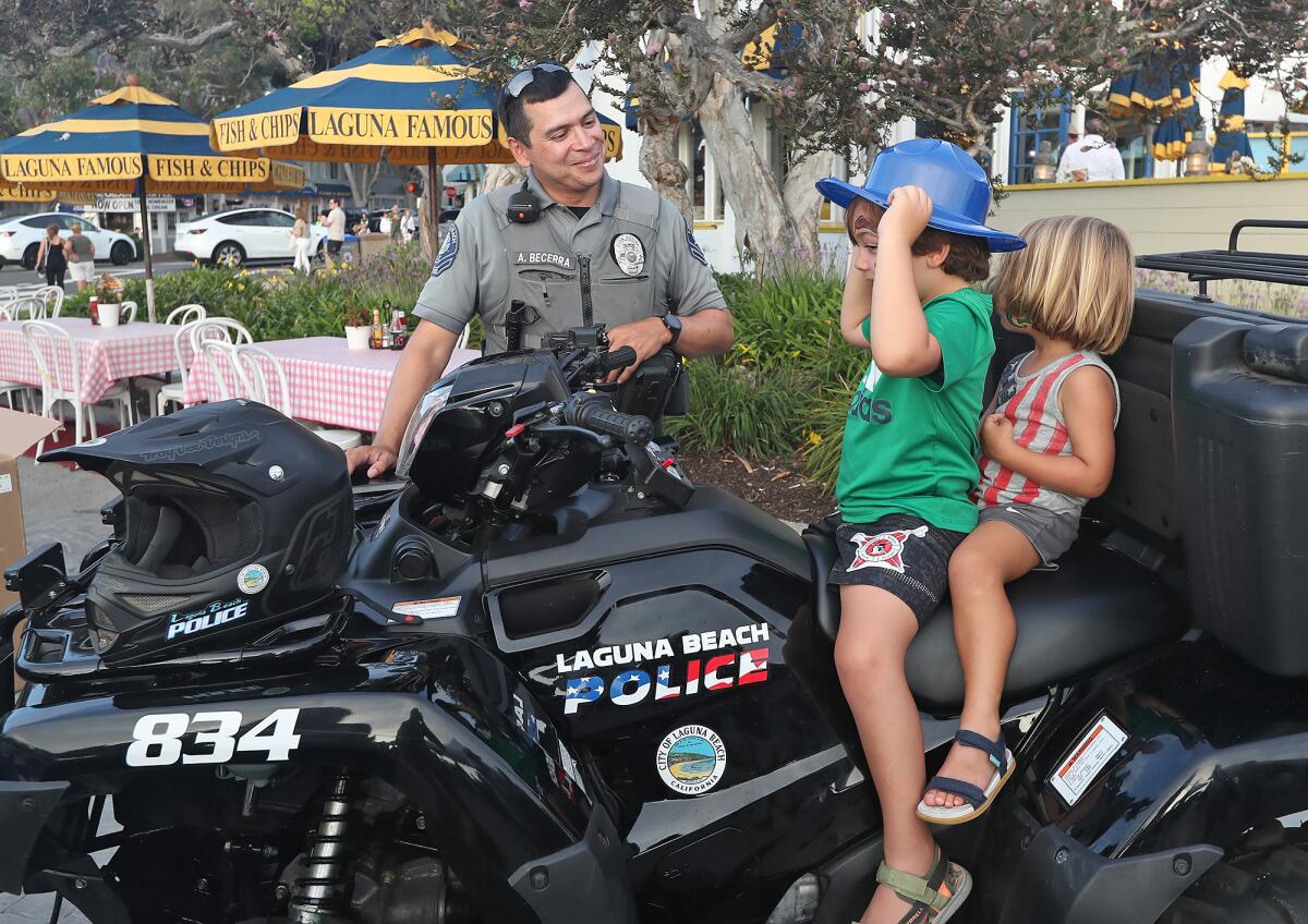 Park Ranger Aureliano Becerra hands out ranger hats to youngsters Benjamin and Matthew, from left, in Laguna Beach.