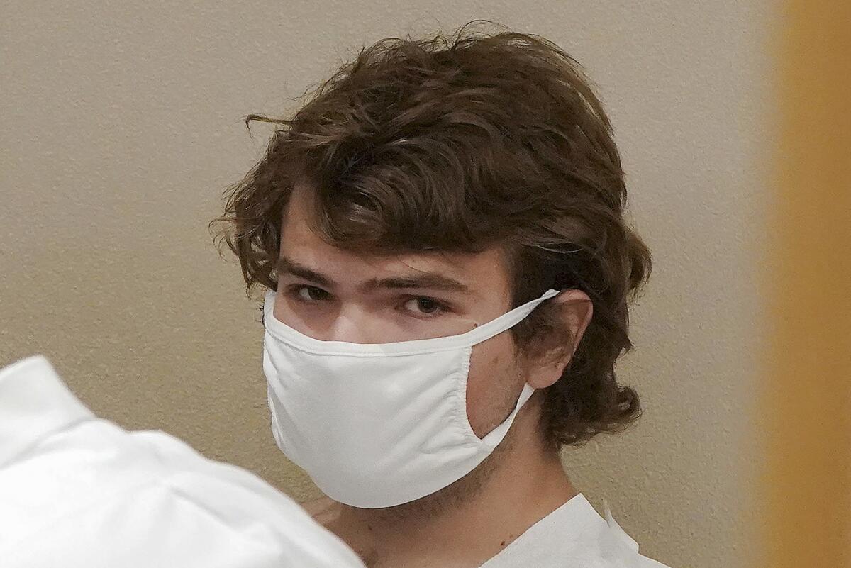 A young man wearing a protective mask and looking into the camera