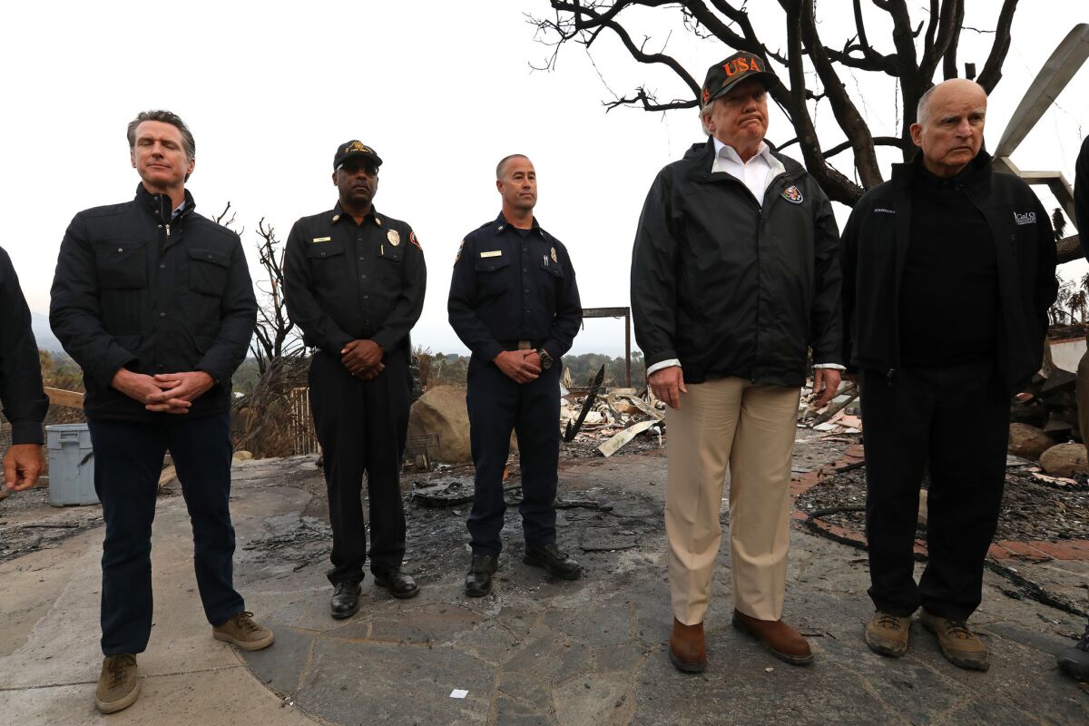 President Trump, on a visit to Malibu on Nov. 17, takes in the damage from the Woolsey fire alongside then-Gov. Jerry Brown. Then-Gov.-elect Gavin Newsom is at left.