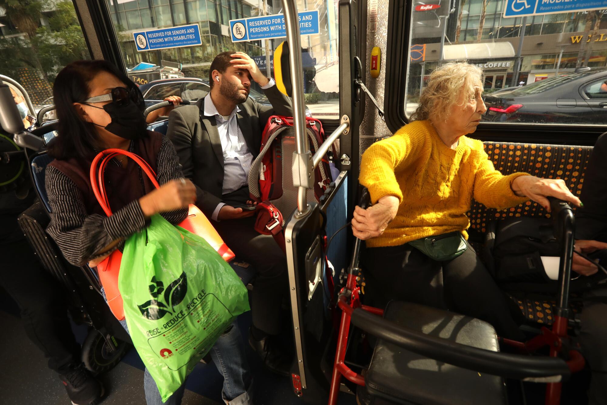 Channah Obadia, 87, right, leaning on her walker for support, rides a Metro bus through the streets of Los Angeles. 