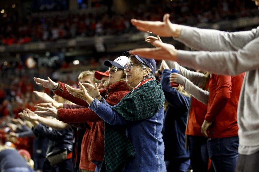 Washington fans do the “Baby Shark” gesture as the Nationals’ Gerardo Parra bats in Game 3 of the World Series.