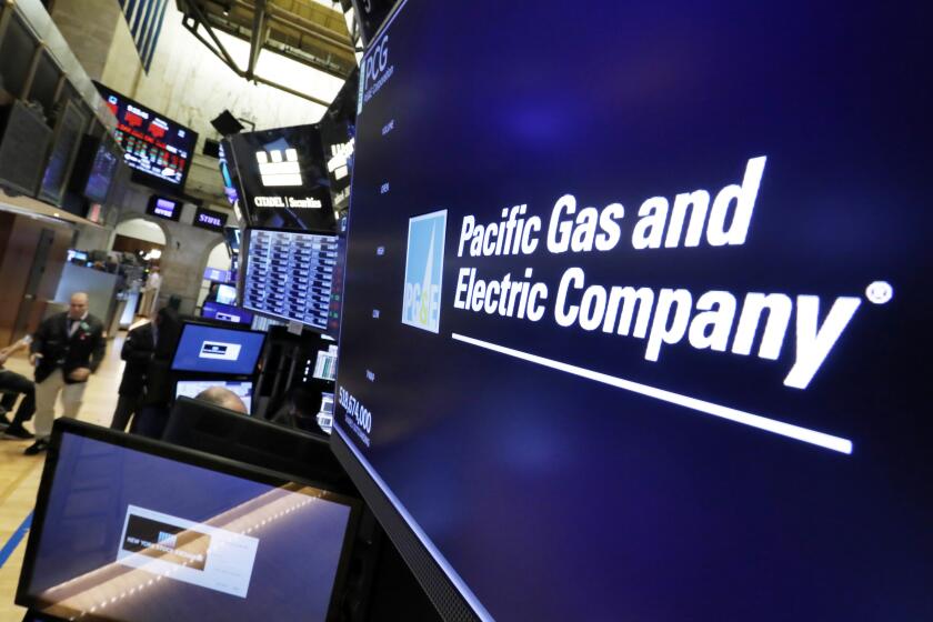 FILE - In this Jan. 14, 2019, file photo the logo for Pacific Gas & Electric Co. appears above a trading post on the floor of the New York Stock Exchange. PG&E says it won't award $130 million in employee bonuses because of its recent bankruptcy filing. The San Francisco Chronicle reported Saturday, Feb. 23, that interim chief executive John Simon cited California's deadly wildfires and the company's precarious financial state in an internal email message to workers on Friday. (AP Photo/Richard Drew, File)
