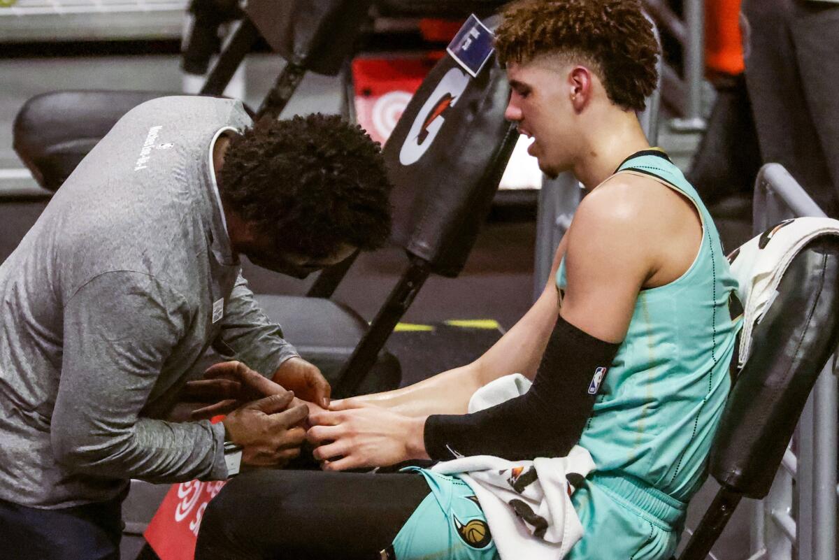 Hornets guard LaMelo Ball has his right wrist tended by a trainer
