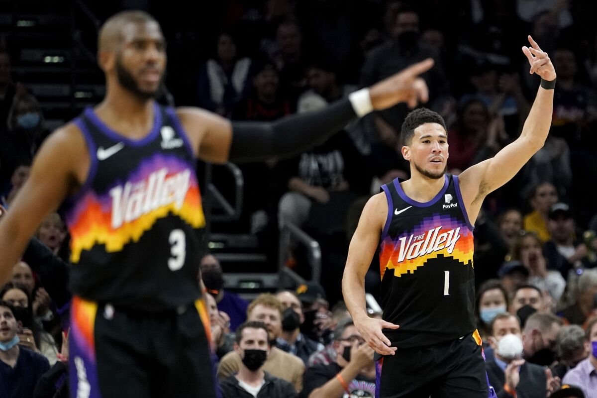 Phoenix Suns guard Devin Booker (1) and guard Chris Paul (3) motion after Booker made a three pointer against the Brooklyn Nets during the second half of an NBA basketball game, Tuesday, Feb. 1, 2022, in Phoenix. (AP Photo/Matt York)
