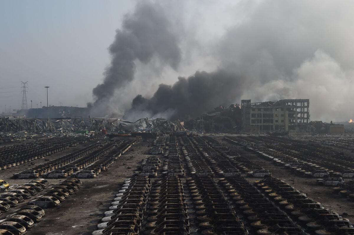 Smoke billows behind rows of burnt-out cars at the site of a series of explosions in Tianjin, northern China, in August.