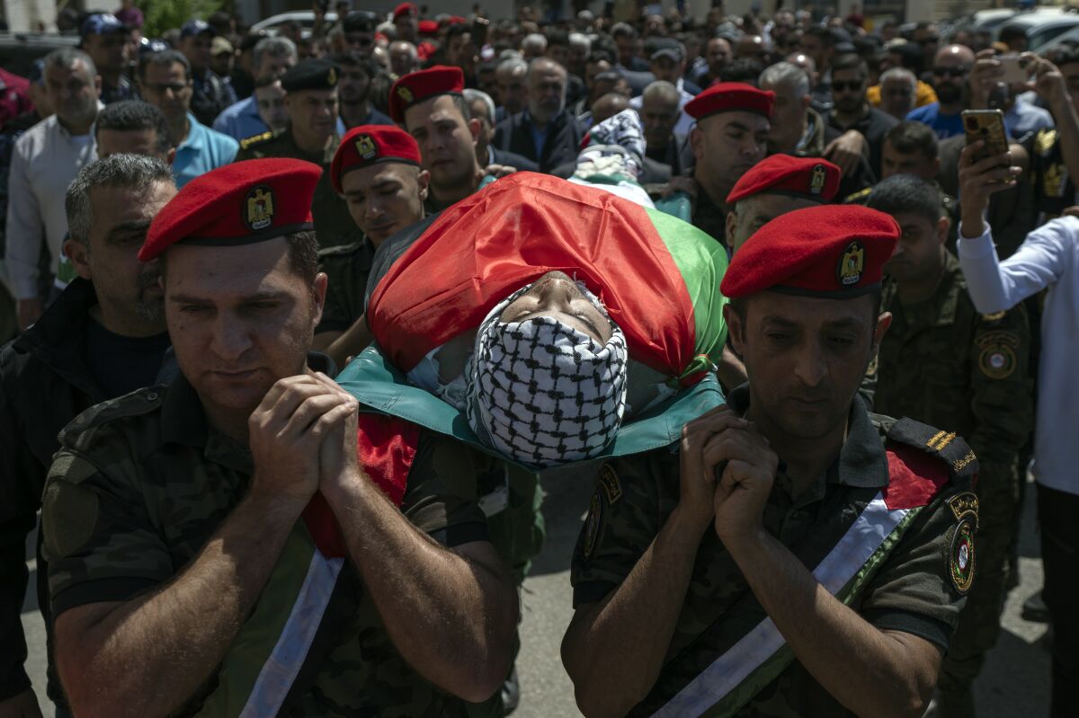 Palestinian security officers carry the body of Muhammad Assaf, during his funeral in the West Bank village of Kufr Laqef, near Qalqiliya, Wednesday, April 13, 2022. Israeli forces shot and killed Assaf, 34, during clashes on Wednesday, the Palestinian Health Ministry said, as Israeli troops continued a days-long operation in the occupied West Bank in response to a spate of deadly attacks. (AP Photo/Nasser Nasser)