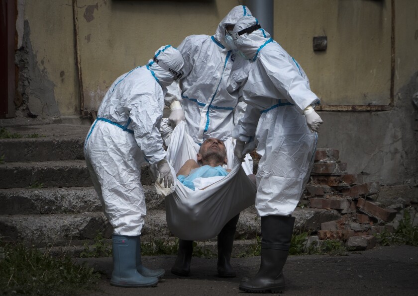 FILE - In this Wednesday, June 3, 2020 file photo, medical workers wearing protective gear to protect against coronavirus infection, carry a patient at infectious diseases hospital where patients with coronavirus are treated in St.Petersburg, Russia. Russia’s updated statistics on coronavirus-linked deaths show that 162,429 people with COVID-19 had died in the pandemic last year, a number much higher than previously reported by government officials. The state statistics agency, Rosstat, released figures for December on Monday, Feb. 8, 2021 updating its count of coronavirus-linked deaths that includes cases where the virus wasn’t the main cause of death and where the virus was suspected but not confirmed. (AP Photo/Dmitri Lovetsky, File)