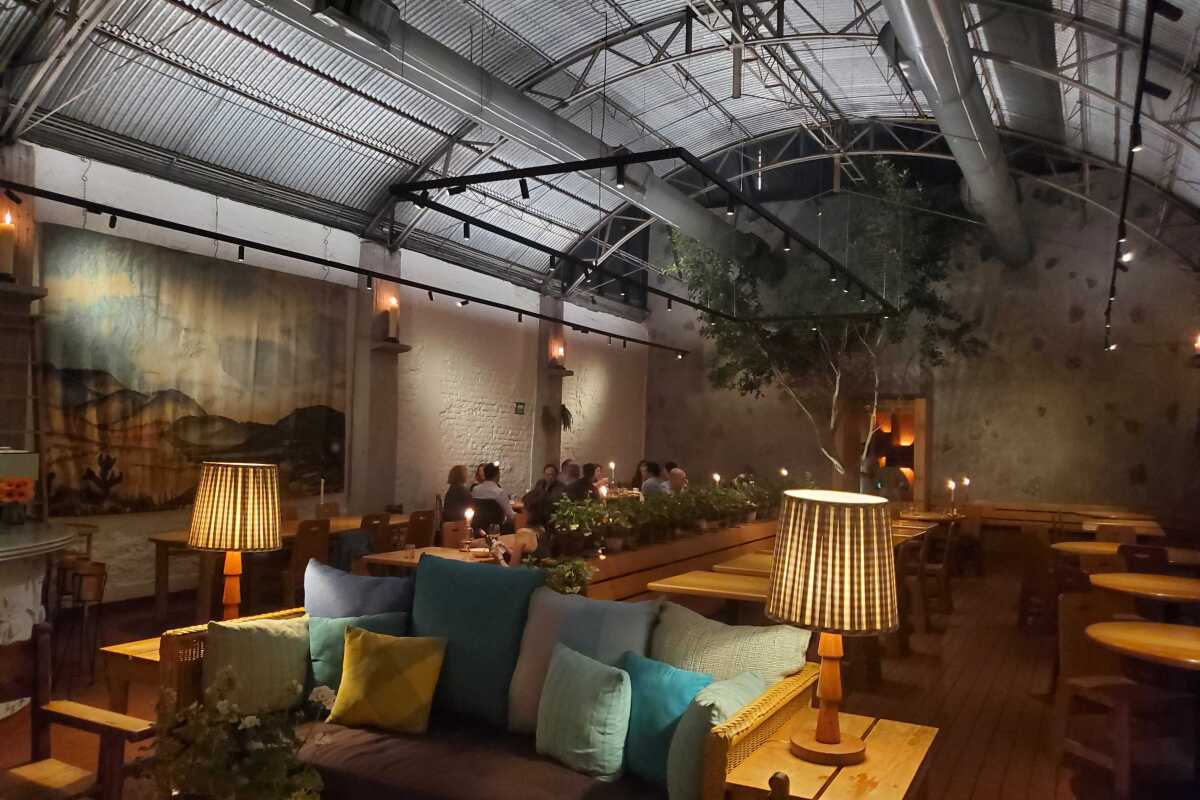 The dimly lit interior of Máximo Bistrot features a metal hangar roof and multiple seating options.