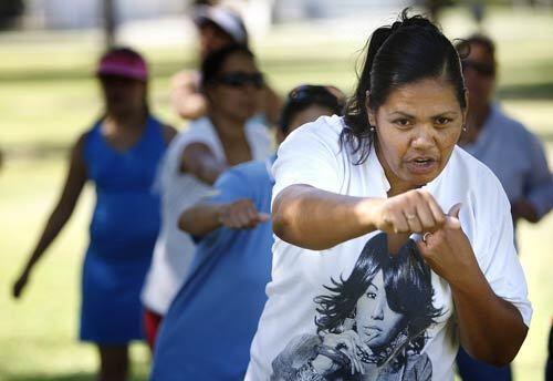 Maria Velasquez, right, punches the air as she leads a group of women in aerobic exercises at the formerly drug- and crime-ridden Stiern Park in Bakersfield.