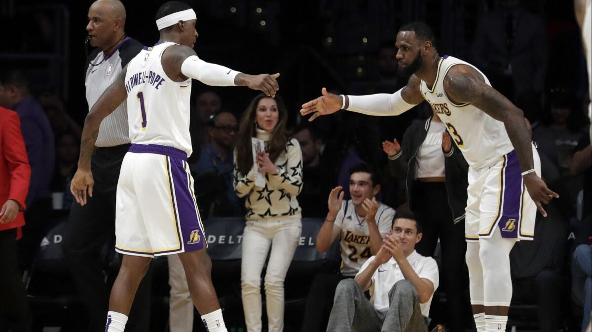 Lakers' Kentavious Caldwell-Pope (1) shakes hands with LeBron James during the first half on Sunday.