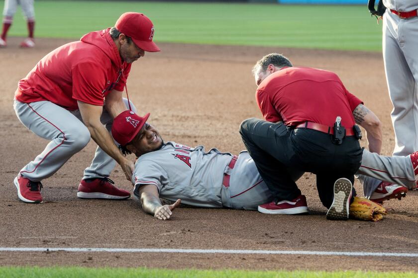 Los Angeles Angels starting pitcher Felix Pena, center, is tended to by trainers after an injury while covering first base during the second inning of a baseball game against the Cleveland Indians in Cleveland, Saturday, Aug. 3, 2019. (AP Photo/Phil Long)