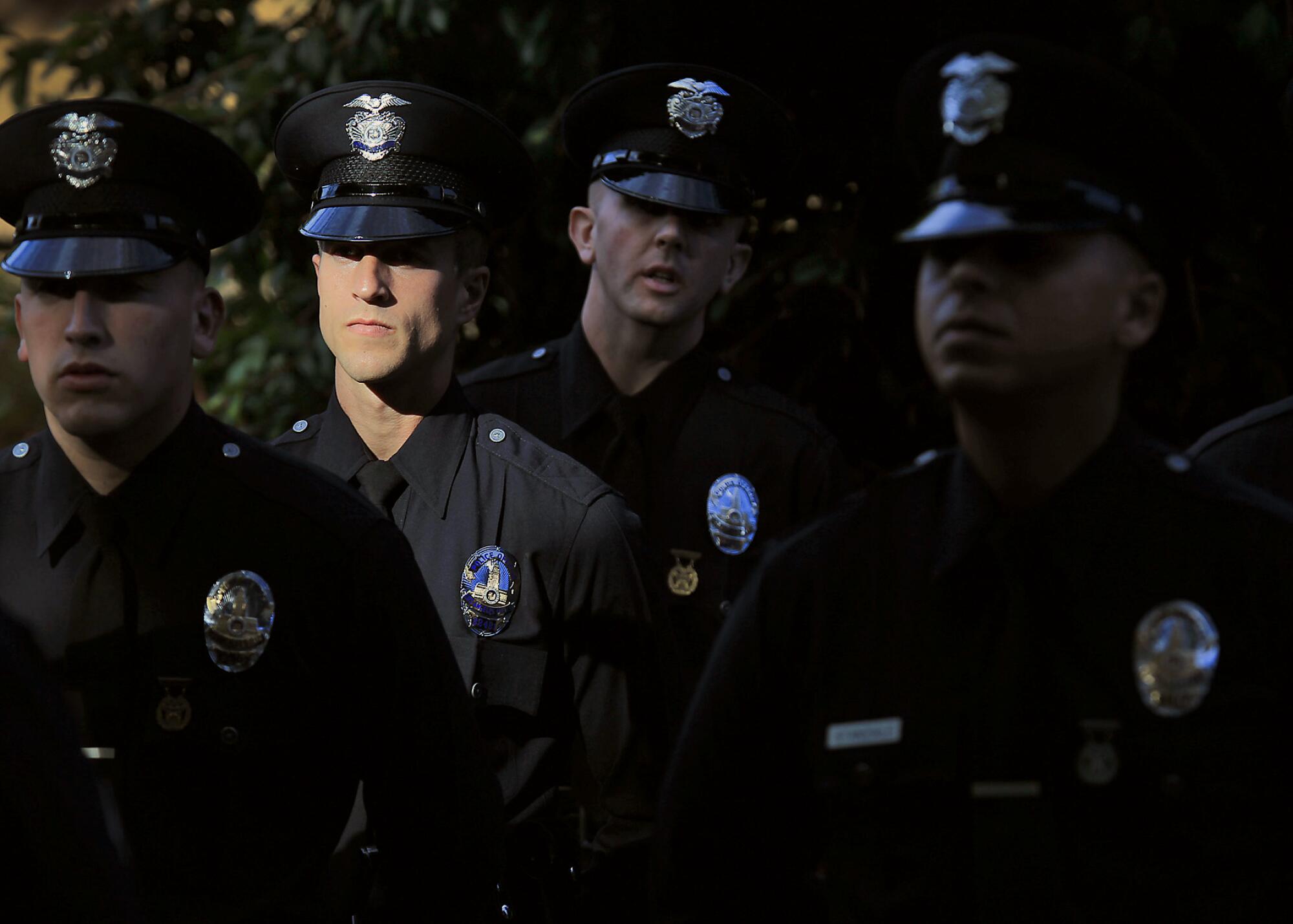 Four LAPD officers stands together, one partially lighted by sunlight.