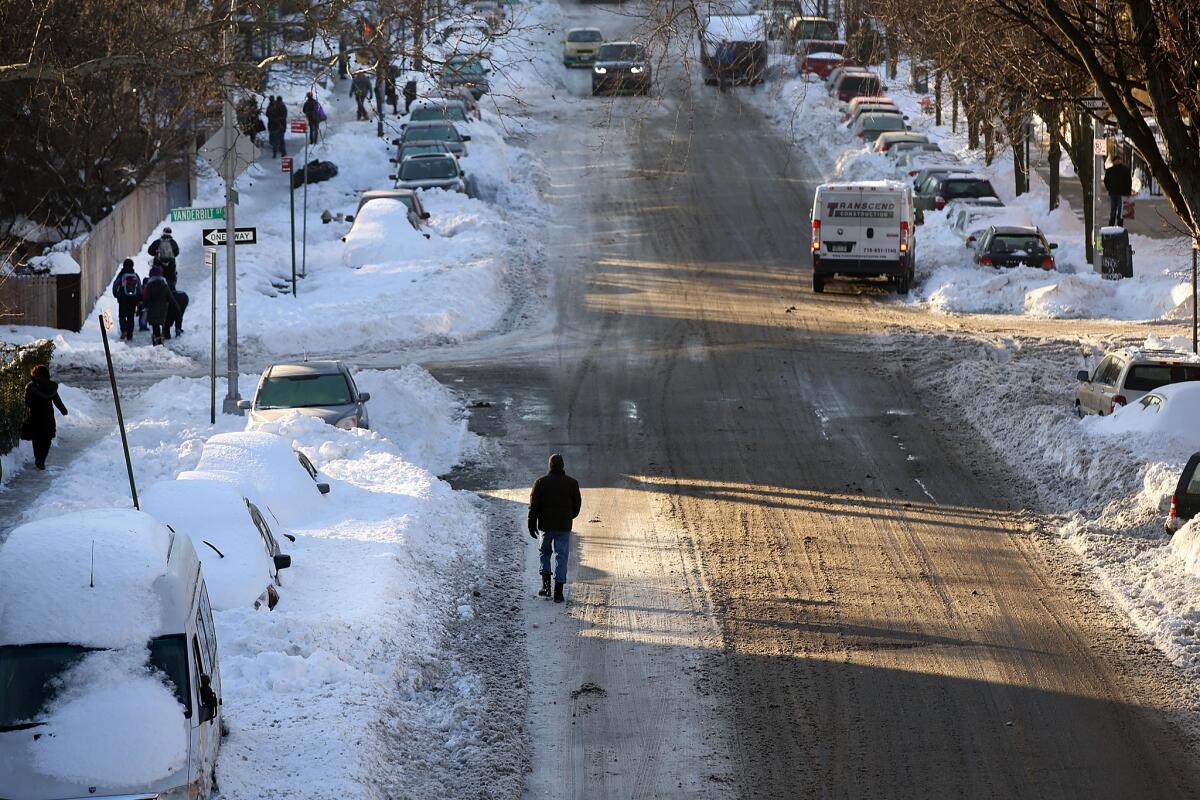 People in New York City walk through the snow on the first workday after the weekend snowstorm.