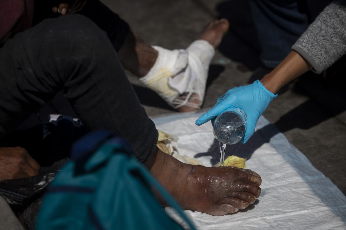 Dr. Susan Partovi, who has practiced street medicine for years, treats a homeless man's ulcerated foot in a Home Depot parking lot in Los Angeles.