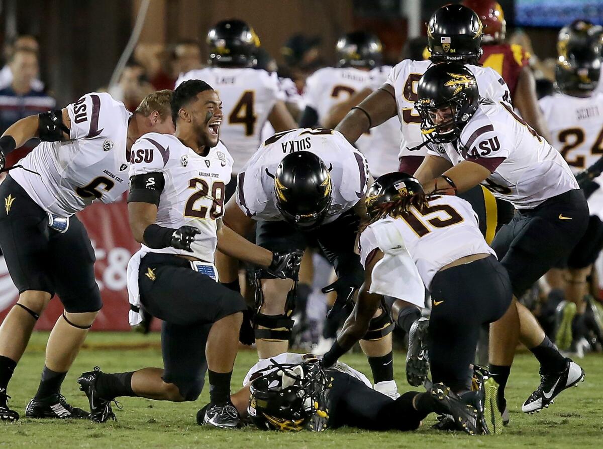 Arizona State quarterback Mike Bercovici (on ground) is about to be engulfed by teammates after throwing a 46-yard touchdown pass on the final play of the game to beat USC, 38-34, on Saturday night at the Coliseum.
