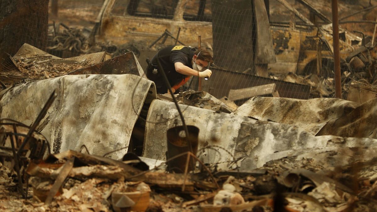 A member of the Sacramento County coroner's office looks for human remains Monday in the rubble of a house burned in the Camp fire.
