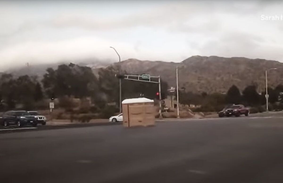 An image taken from video shows a porta-potty rolling down a busy intersection in Albuquerque, N.M.