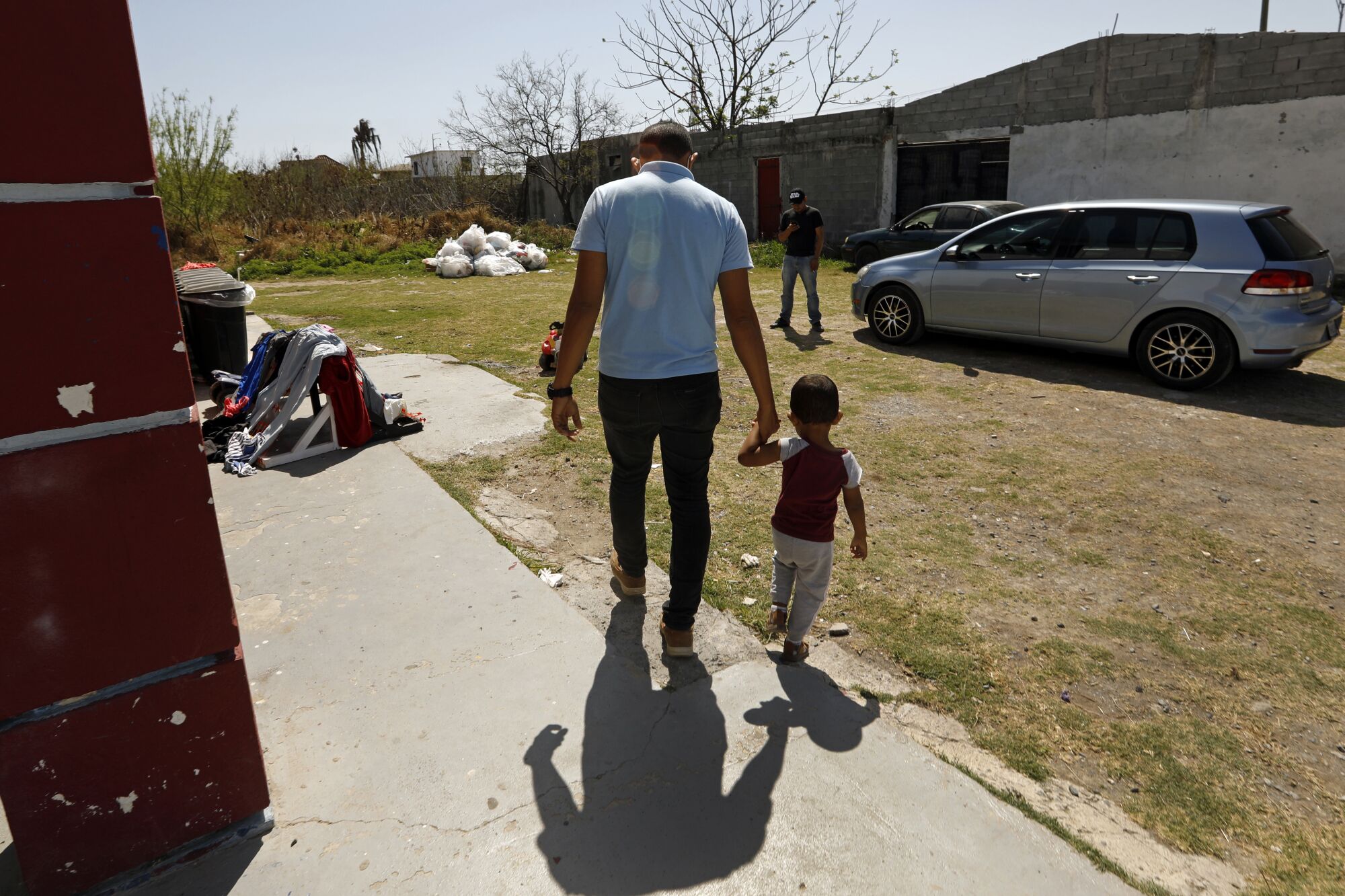 A man and his son, 2, walk outside a shelter. 