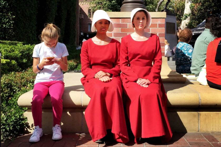 Actresses in costume and character from the Hulu series "The Handmaid's Tale," based on the book by Margaret Atwood, plant themselves in various spots around the USC campus during the Los Angeles Times Festival of Books at the USC campus on Sunday, April 23, 2017 in Los Angeles, Calif. (Ken Kwok/ Los Angeles Times)