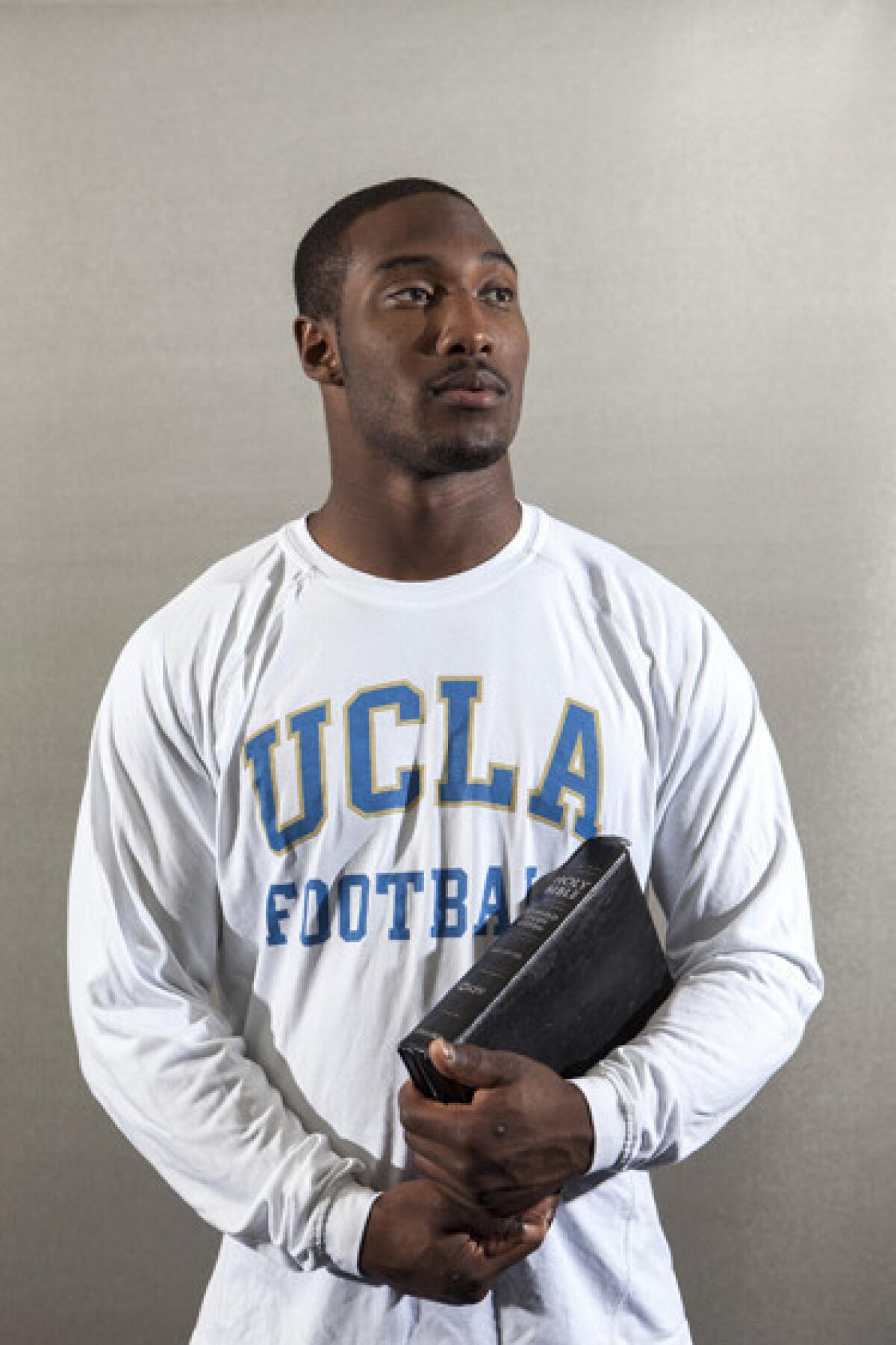 Johnathan Franklin, a senior running back on UCLA's football team, is photographed holding a Bible and football.