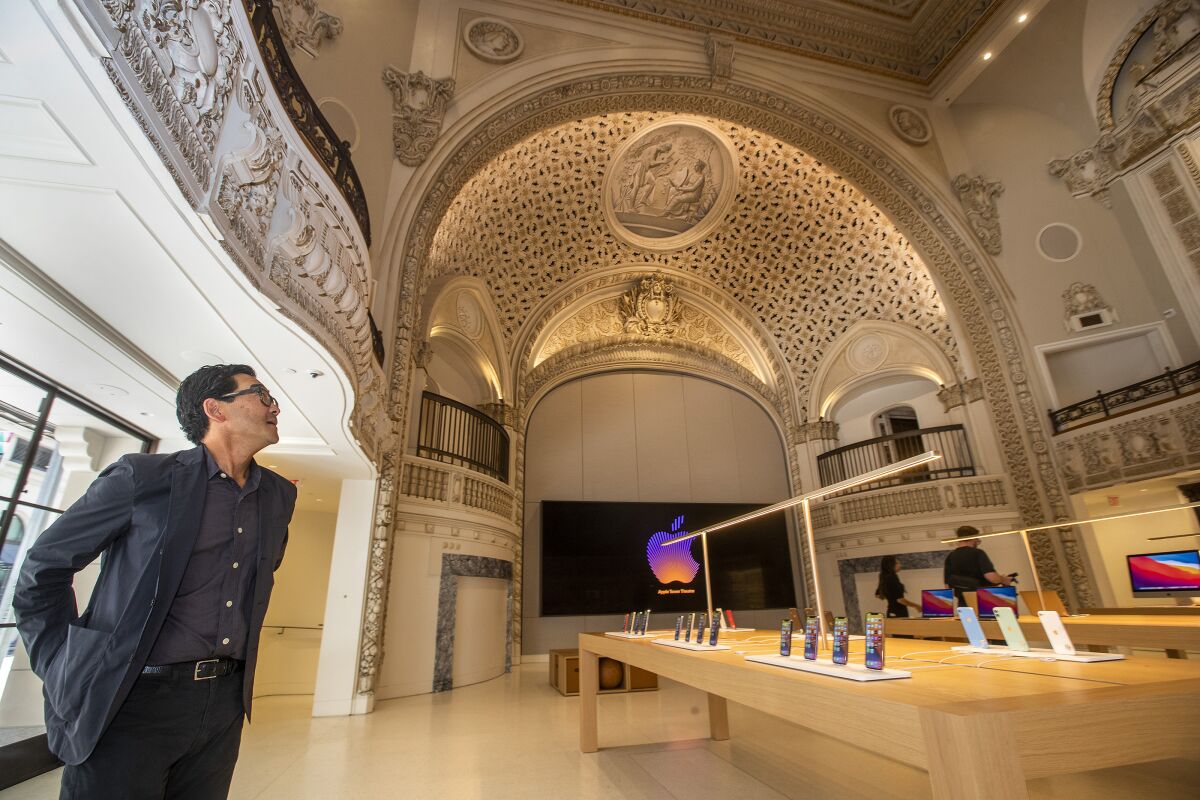 A man looks up at the new ornate Apple store in downtown L.A. with tables and merchandise in it.