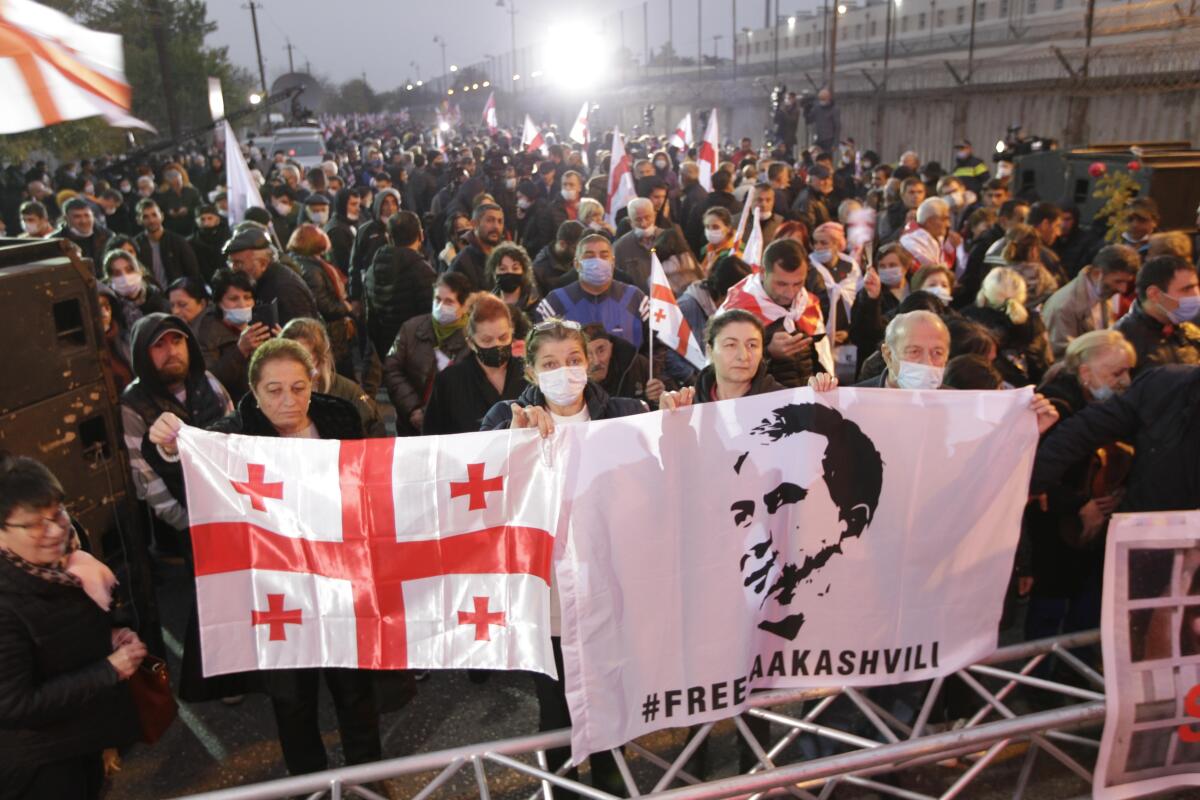 Georgian opposition supporters of former president Mikheil Saakashvili hold national flags and posters with his portraits during a rally in front of the prison where the former president is being held, in Rustavi, about 20 km from the capital Tbilisi, Georgia, Saturday, Nov. 6, 2021. Saakashvili was detained in Tbilisi on Saturday, Oct. 1, 2021. Doctors say former President Mikheil Saakashvili is very weak as he nears 40 days on hunger strike. He started the hunger strike after being arrested at the beginning of October when he returned to Georgia. Saakashvili, who left Georgia in 2014 and became a Ukrainian citizen, faces several charges in Georgia and earlier was sentenced in absentia to up to six years in prison. (AP Photo/Shakh Aivazov)