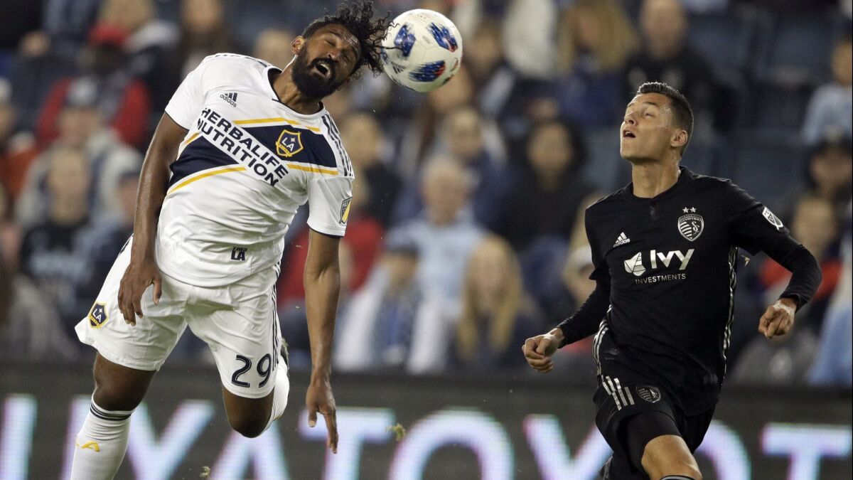 Galaxy defender Sheanon Williams (29) heads the ball away from breaking Sporting Kansas City forward Daniel Salloi, right, during the first half on Saturday.