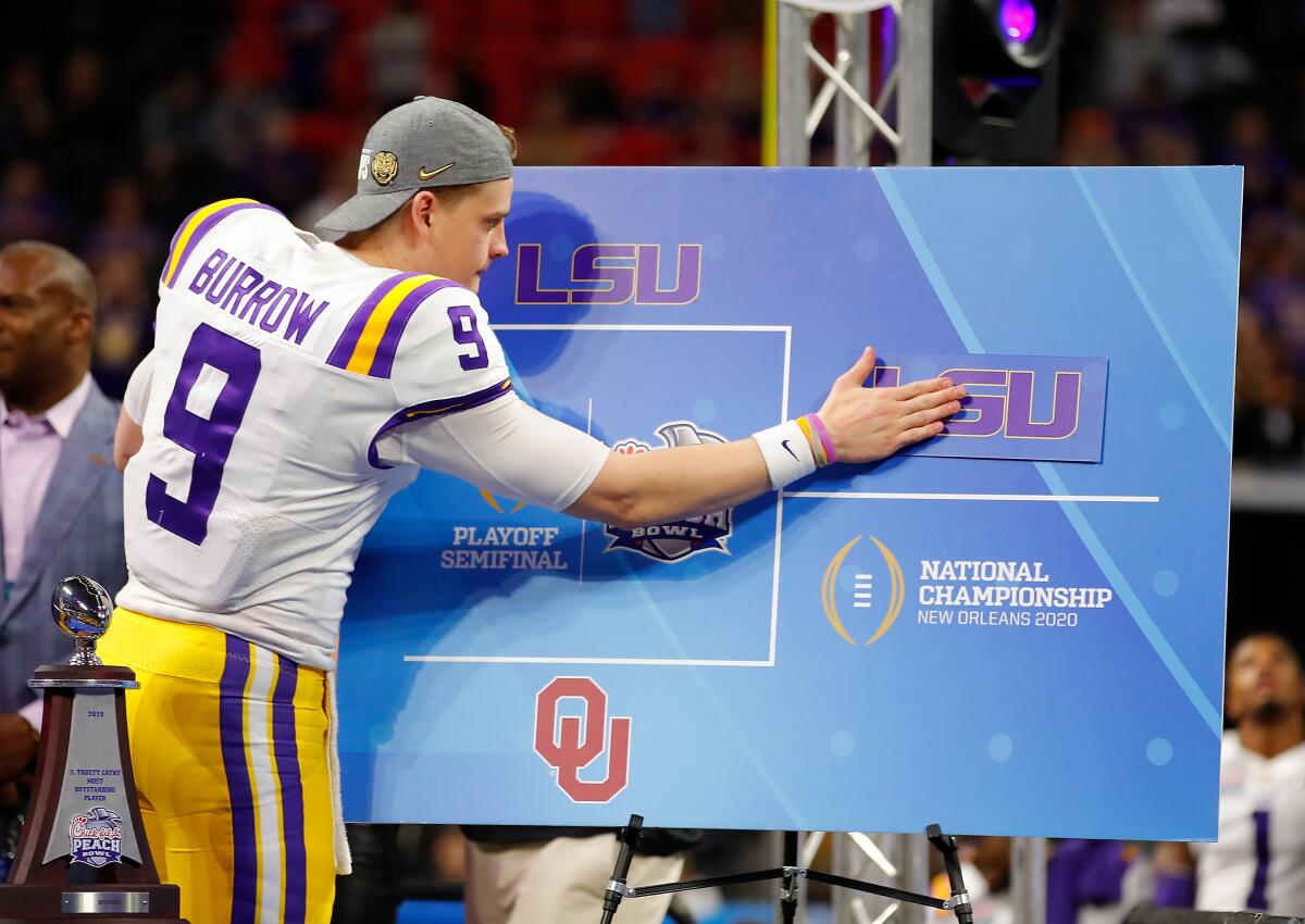 LSU quarterback Joe Burrow posts the LSU sticker on the bracket board to indicate advancing to the National Championship.