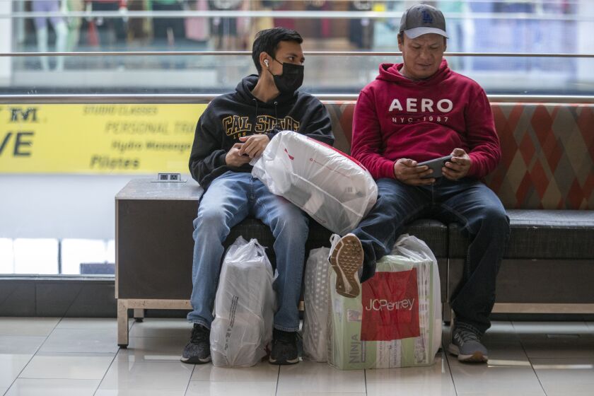 Glendale, CA - November 25: Kevin Guerrero, left, and Rafael Guerrero, right, relax as they sit next to their shopping bags at the Glendale Galleria on Black Friday, Nov. 25, 2022, in Glendale, CA. (Francine Orr / Los Angeles Times)